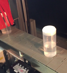 Plastic bottle exits heat tunnel with sealed shrinkband
