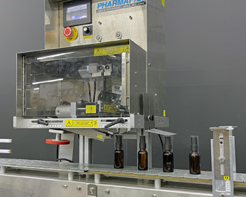 Pharmafill NB1 neck banding machine applying shrinkbands to dropper bottles