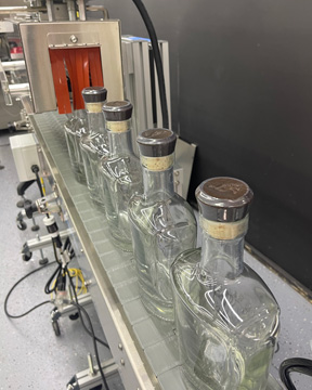 Pharmafill HT6B heat tunnel with sealed shrinkbands on glass bottles with conveyor