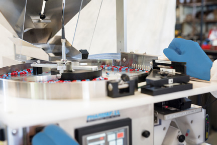 Machine operator using the Pharmafill TC4 tabletop tablet counter wearing blue gloves