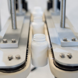 Deitz Pharmafill Bottomless Conveyor transferring white vitamin bottles