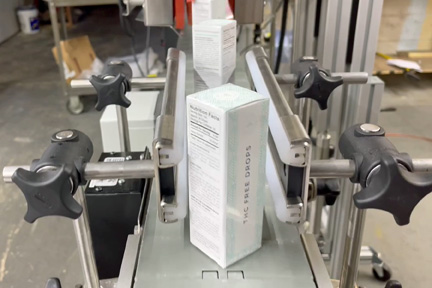 Square containers exit the Pharmafill HT6B heat tunnel sealed with tamper-evident bands